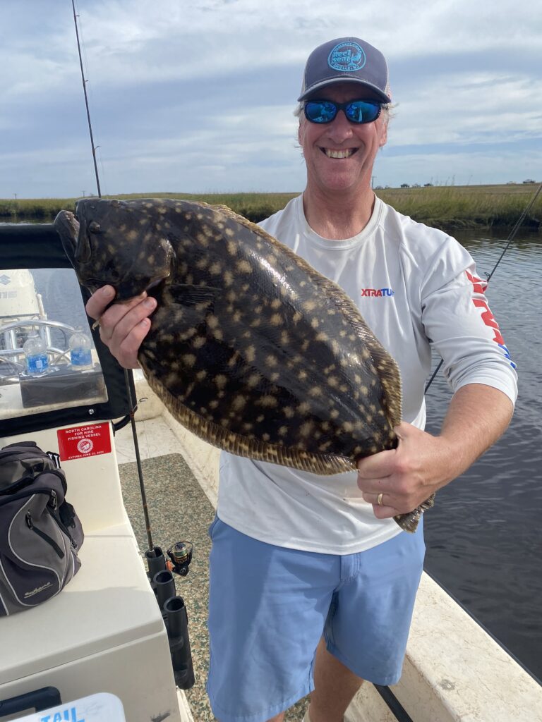 Photo Courtesy of Topsail Island Fishing Guides | Captain Mike Hoffman | Male angler holding a large flounder.