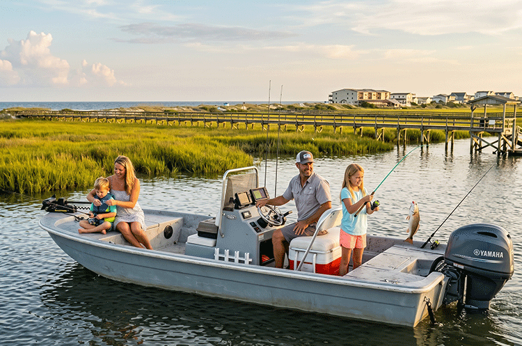 A family fishing together on a boat in the calm waters of the Topsail Island sound at sunset.