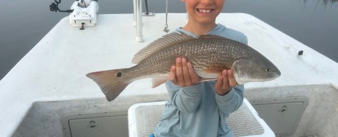 June 13 Topsail Fishing Report | Young angler holding a red drum fish from Topsail Island Fishing Charters.