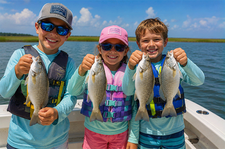 Young anglers holding a Spot caught near Topsail Island during a family-friendly fishing trip in local sound waters.