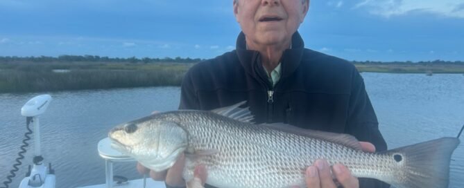 Angler holding a large red drum aboard a fishing boat in the inshore waters near Topsail Island, North Carolina